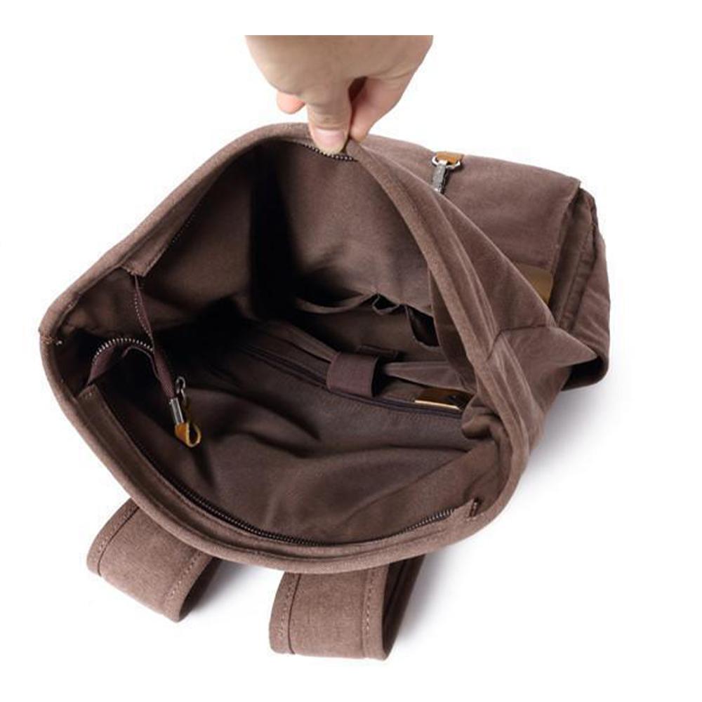 Hand holding open the Coffee waxed canvas backpack to show its lining and inner pockets.