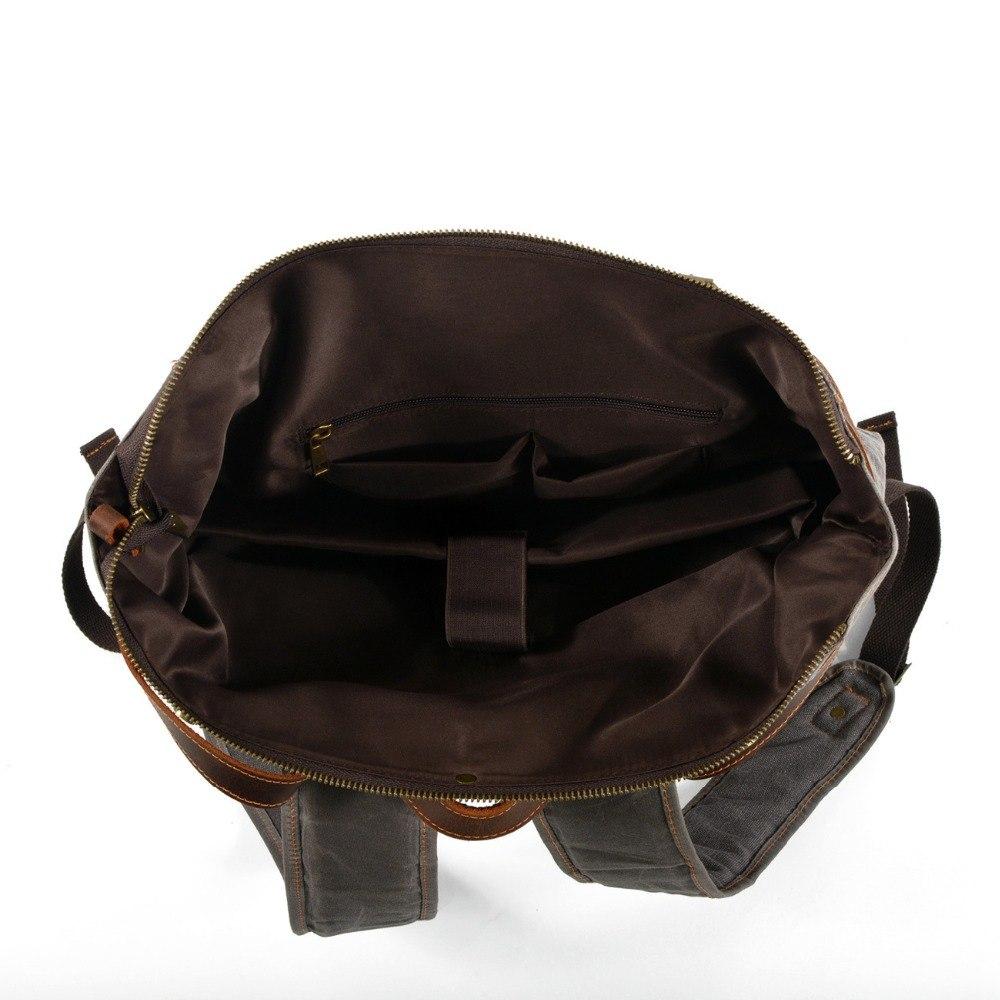 Open interior of gray waxed canvas backpack with dark lining, padded laptop sleeve and organizer pockets.