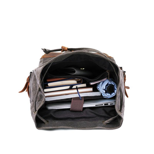 Open gray backpack packed with books and a laptop in the main compartment