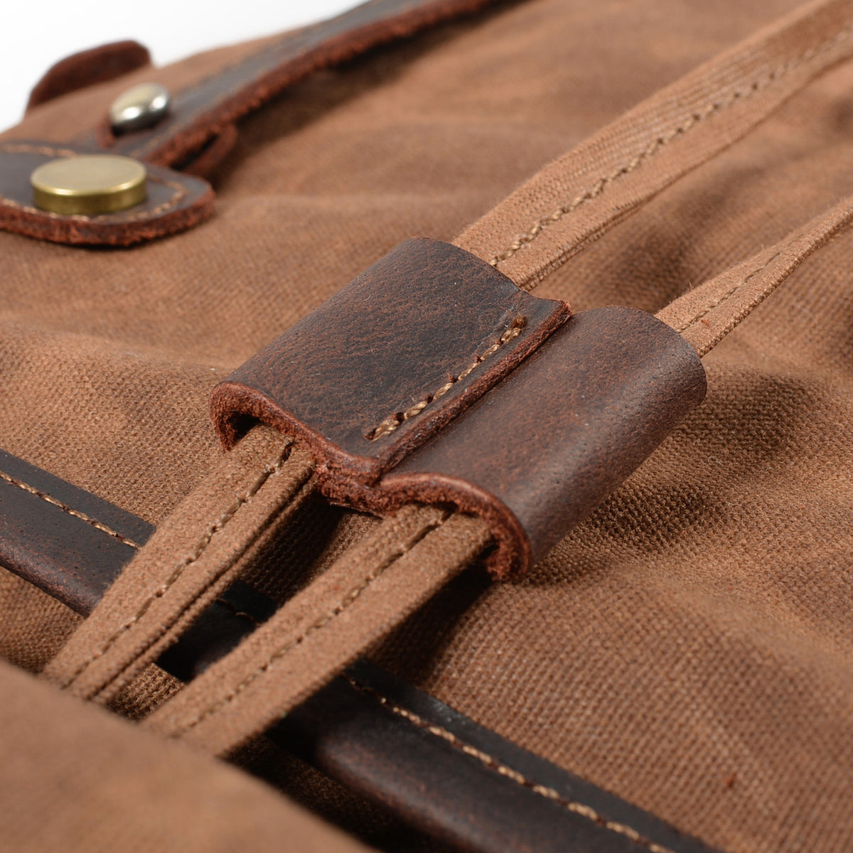 Coffee waxed canvas backpack close-up of the leather loop holding the drawstring cord.