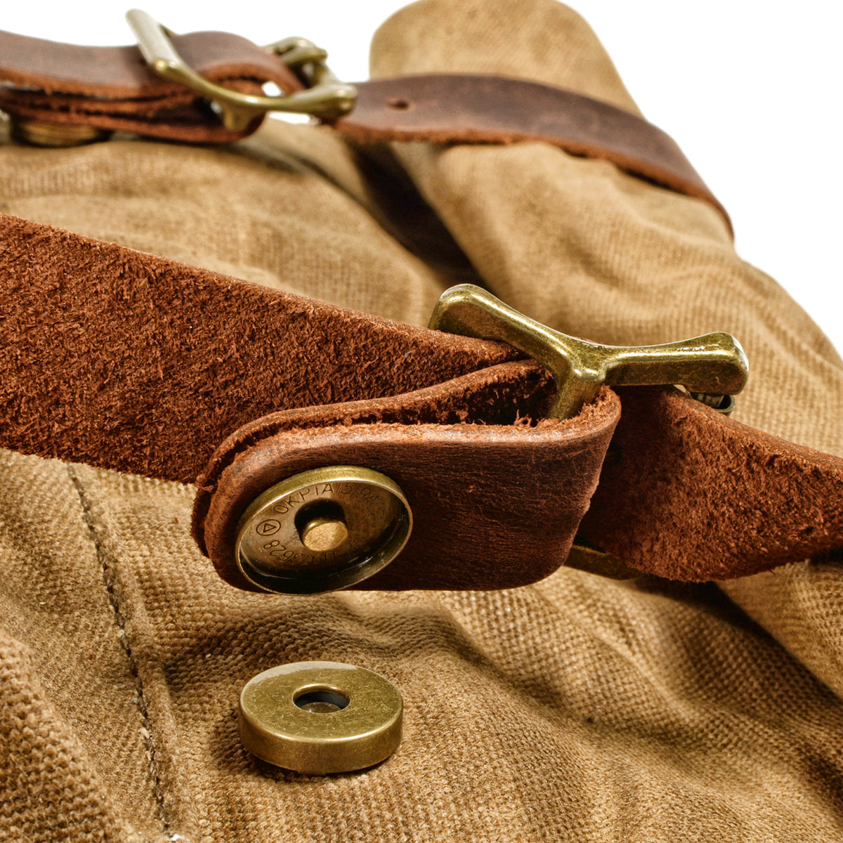 Open magnetic snap under a leather strap, with the brass hook closure visible