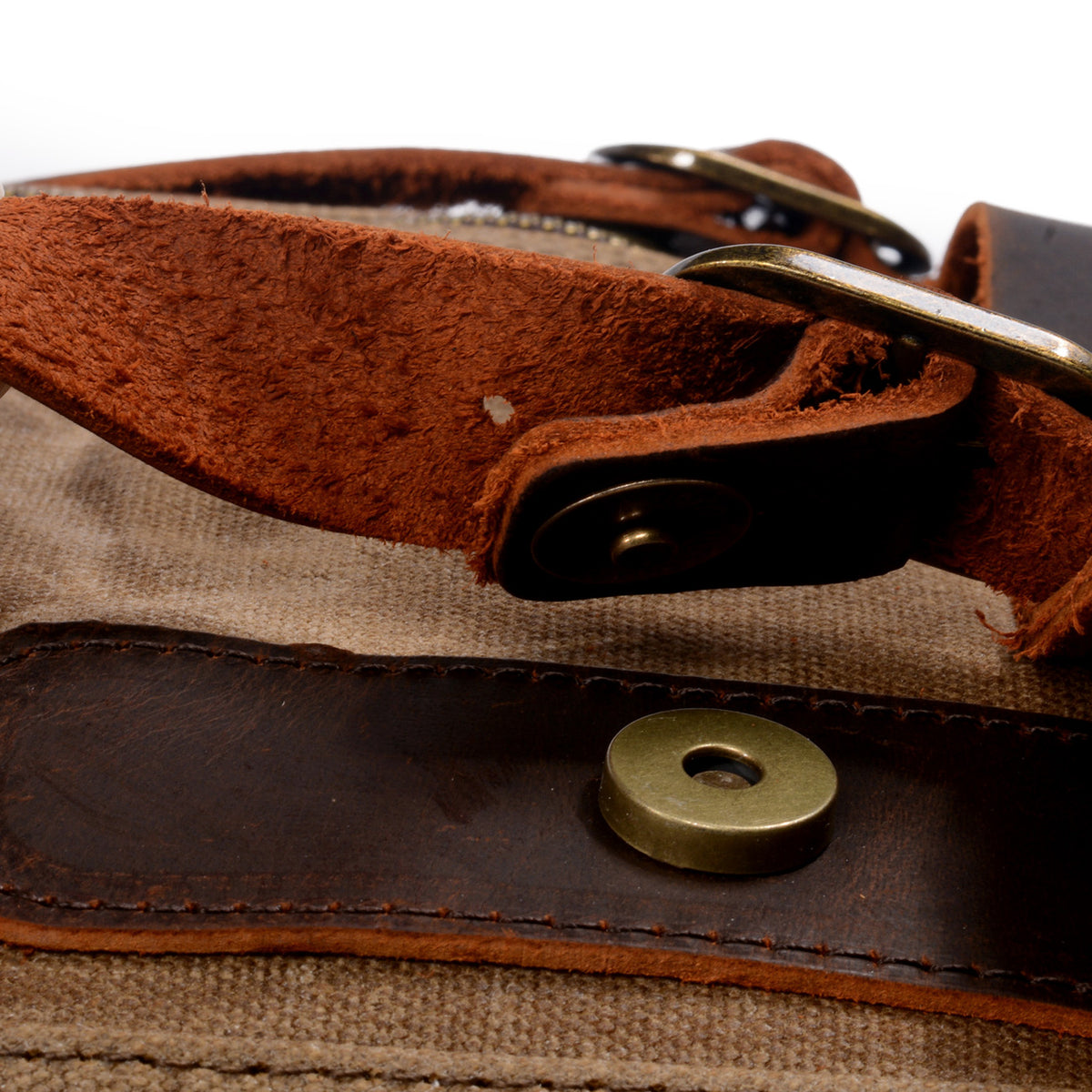 Brass magnetic snap under the leather strap of the khaki backpack