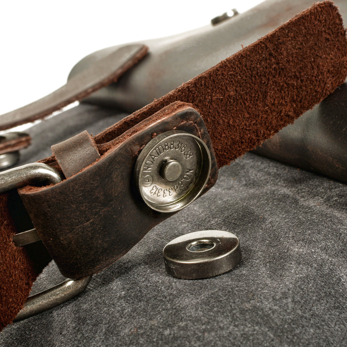 Brass magnetic snap under the leather flap of the gray backpack