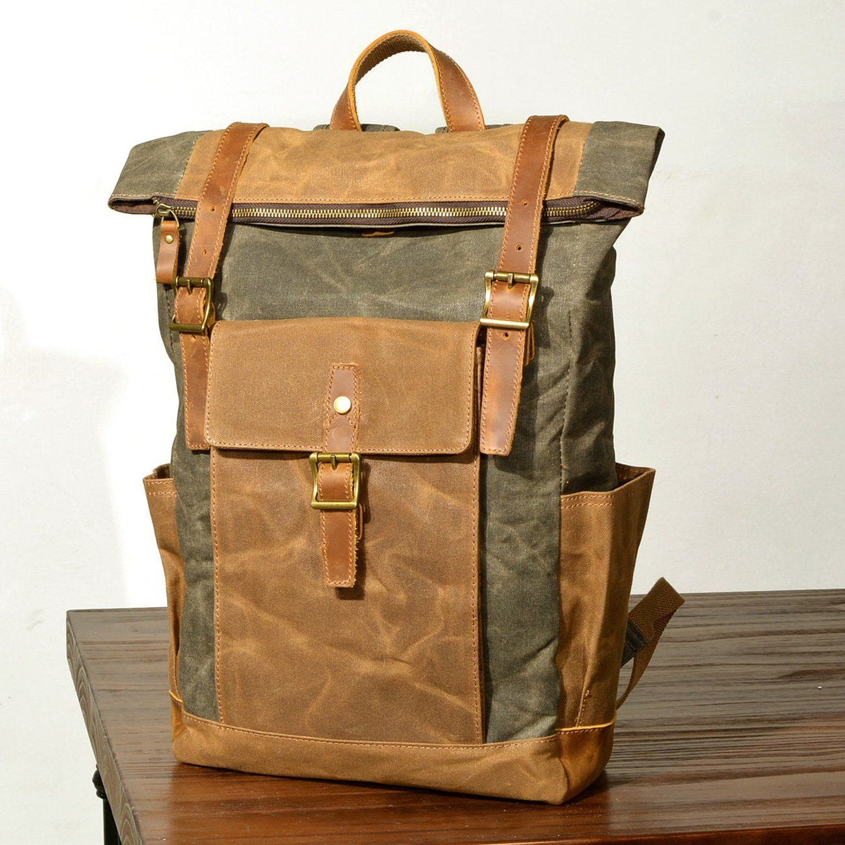 Army green waxed canvas backpack standing on a wooden table