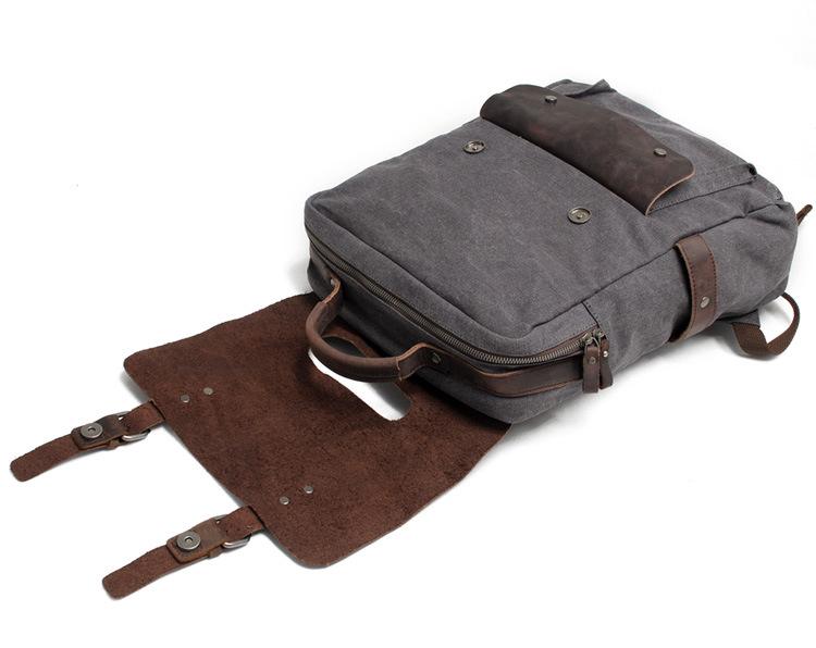 Dark gray canvas backpack with the leather flap folded open.