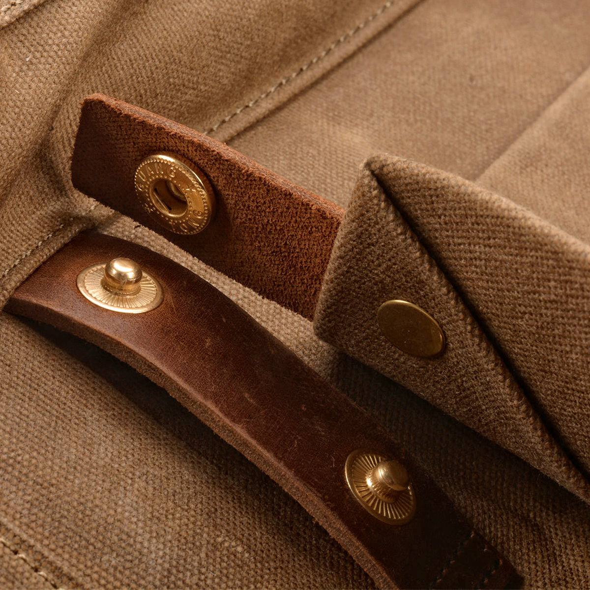 Brass snap on a leather strap of the khaki backpack