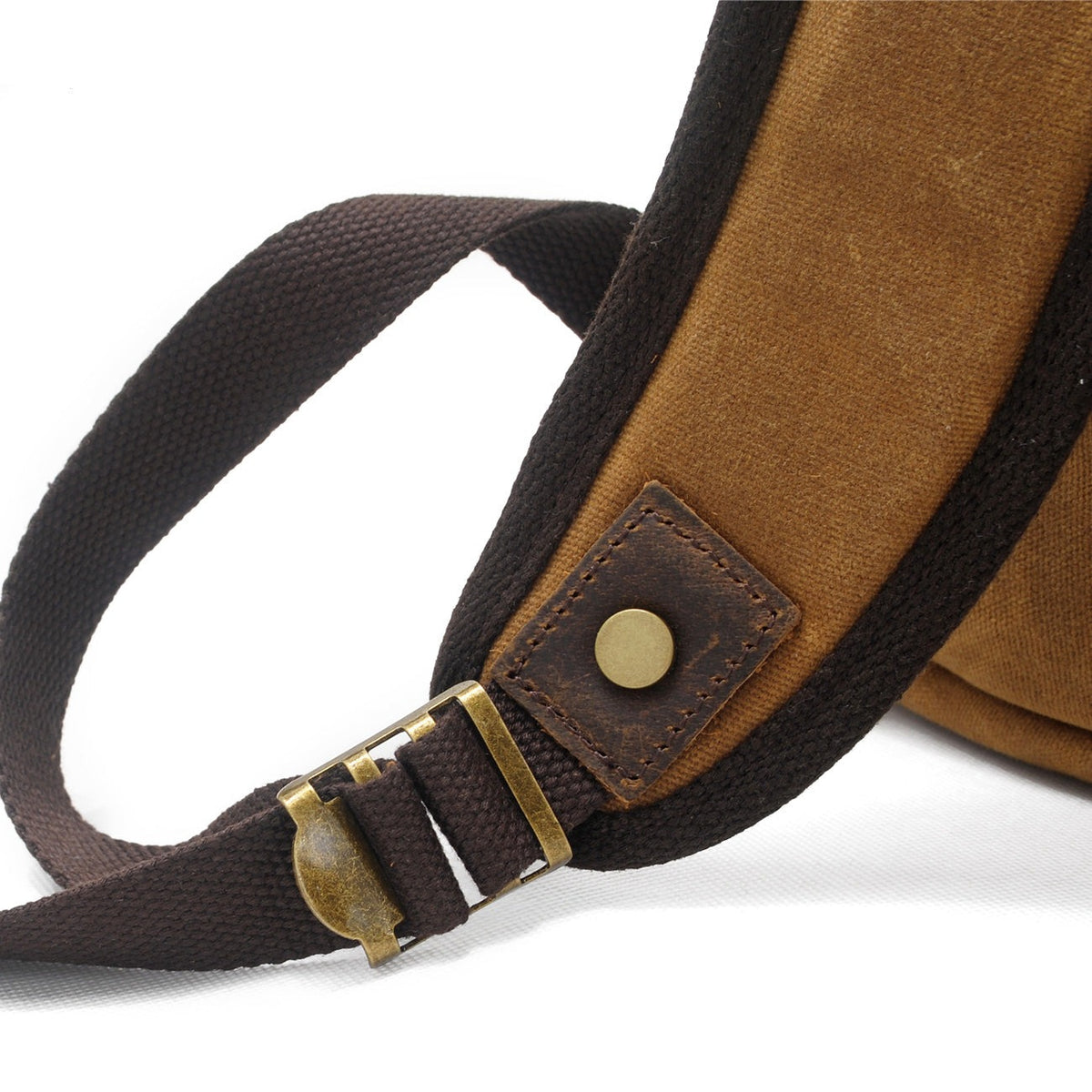 Riveted shoulder strap and brass slider on the khaki backpack