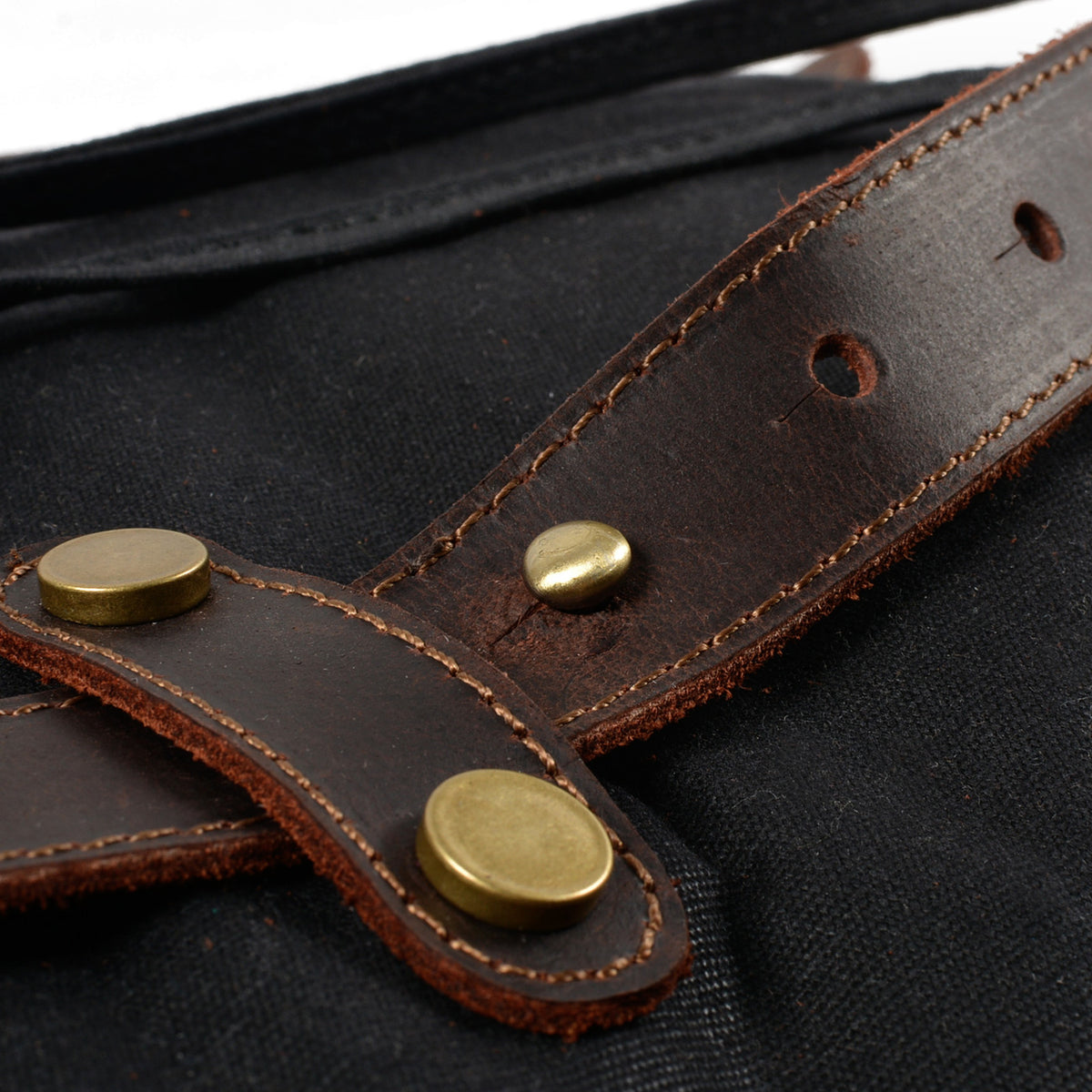 Riveted crazy horse leather strap tab on black waxed canvas