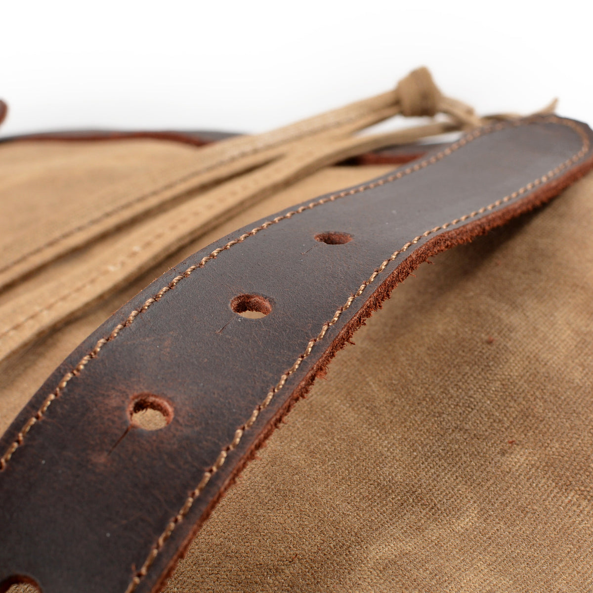 Punched leather strap resting on the khaki canvas flap