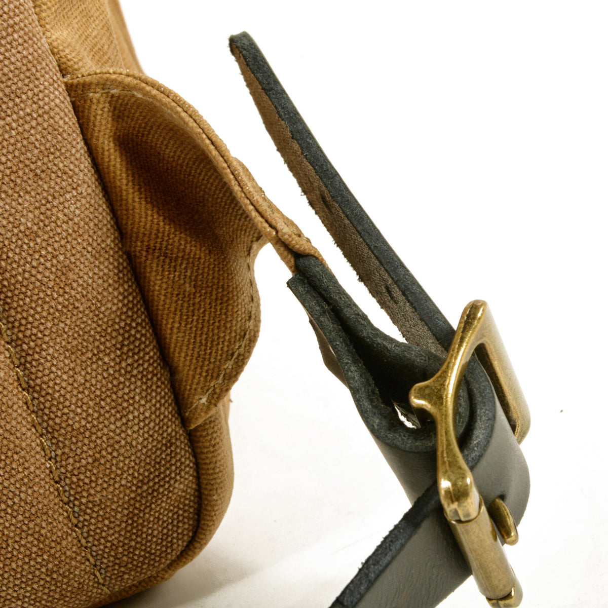 Brass buckle on the leather shoulder strap of the khaki backpack