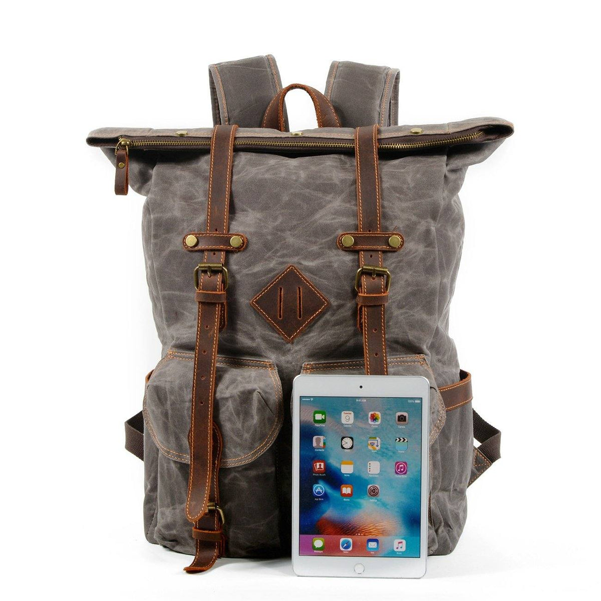 Gray waxed canvas roll top backpack with a white tablet in front for size comparison.