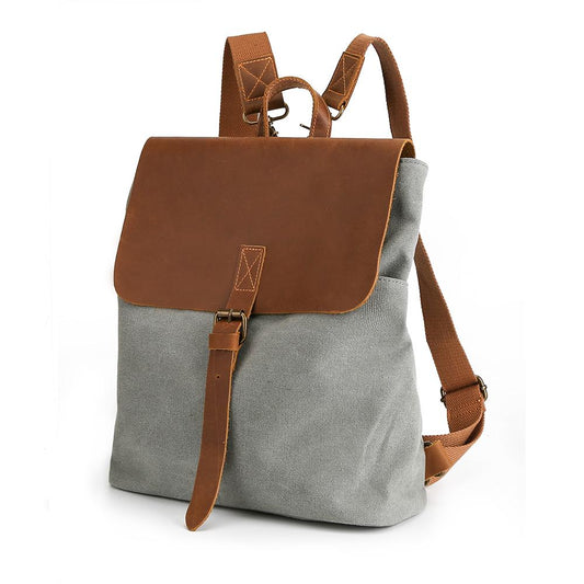 Gray canvas backpack at an angle, showing leather flap and convertible shoulder straps.