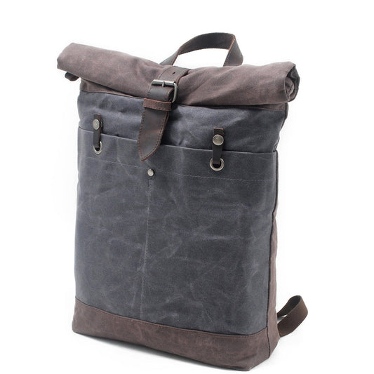 Three-quarter view of the Gray roll top backpack with its front buckle pocket.