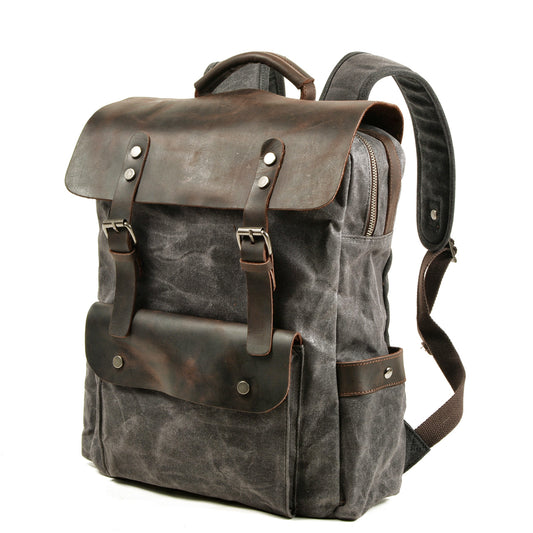 Three-quarter view of the Gray backpack with its padded shoulder strap and leather front pocket.