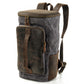 Three-quarter view of the gray waxed canvas backpack showing its tall body and leather grab handle