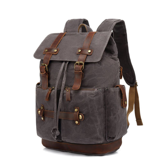 Three-quarter view of the Gray waxed canvas laptop rucksack with leather straps and front pockets.