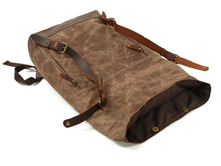 Unrolled backpack laid flat, showing an open mouth and unfastened leather straps
