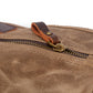 Close-up of the brass zipper pull with a leather tab on the khaki canvas