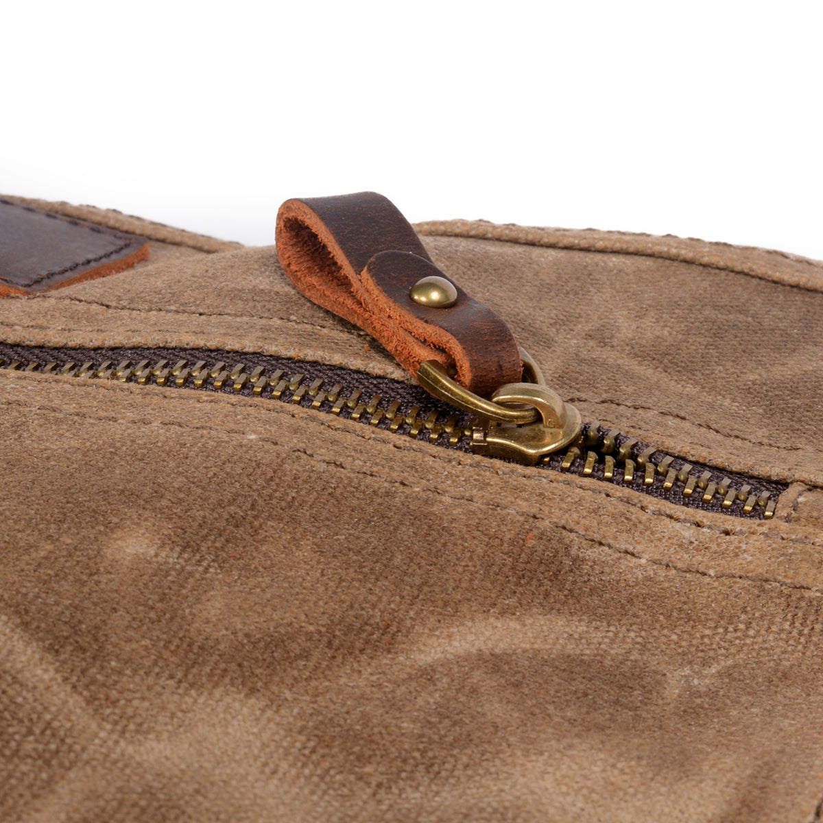 Close-up of the brass zipper pull with a leather tab on the khaki canvas