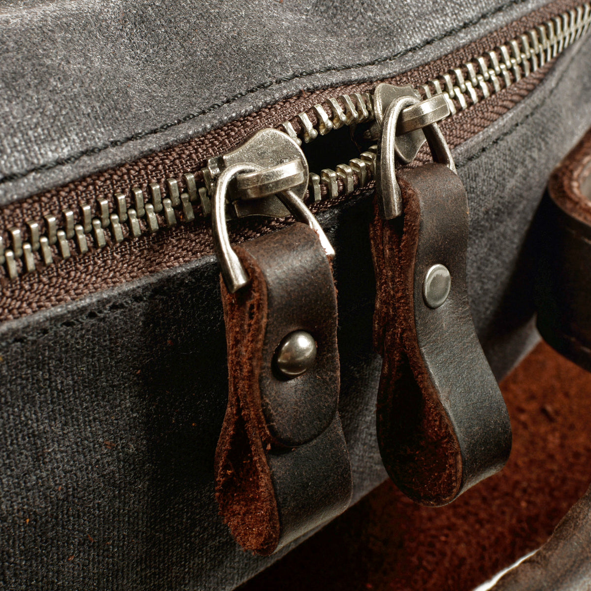 Close-up of the zipper pulls with leather tabs on the gray backpack