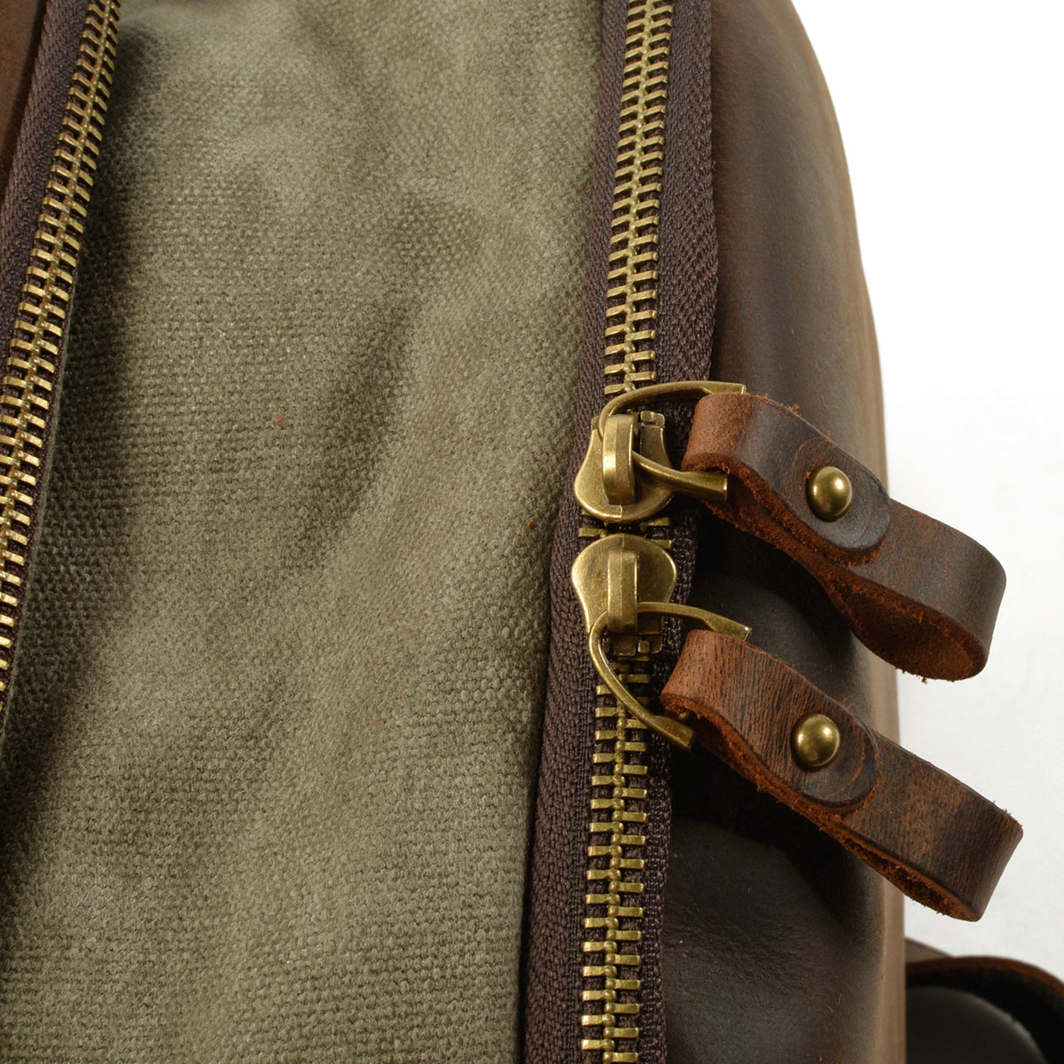 Twin brass zipper pulls with riveted leather tabs at the top opening