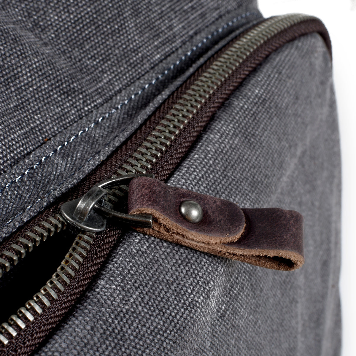 Zipper teeth and a riveted leather pull tab on the canvas backpack
