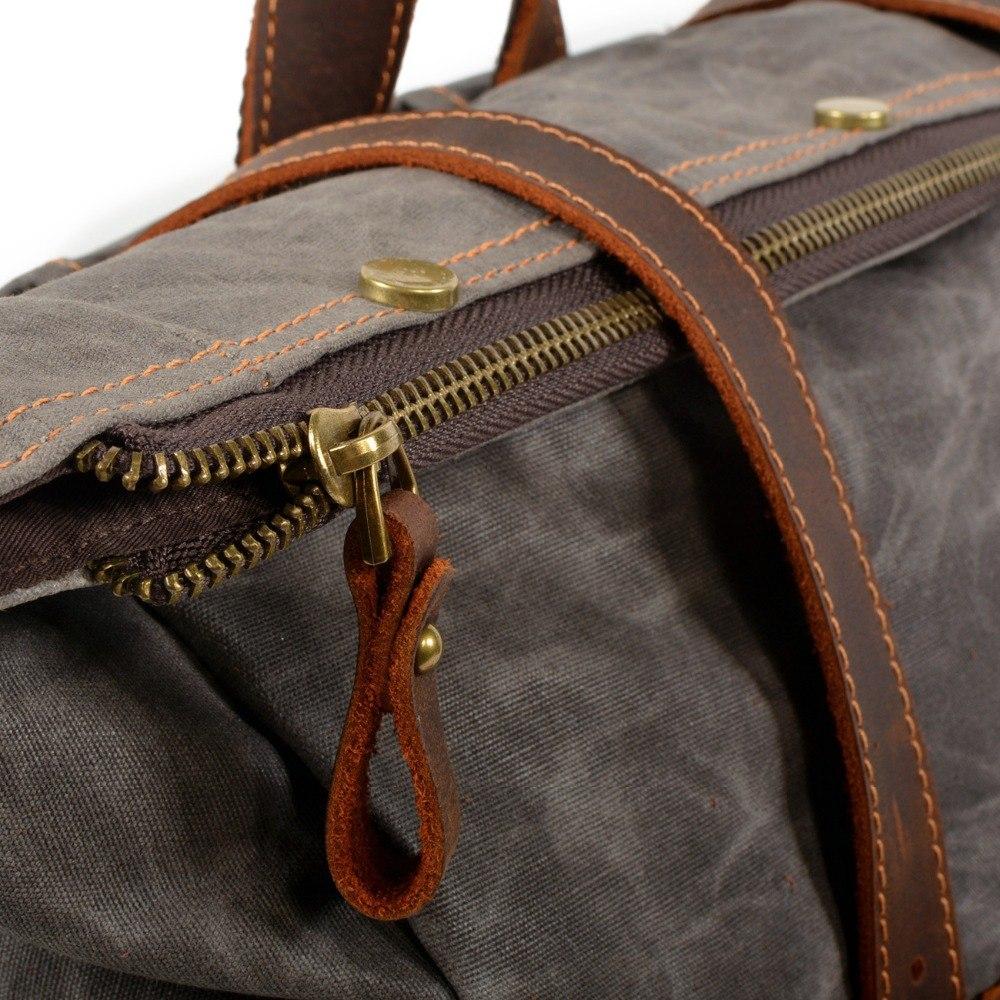 Brass zipper at the top of gray waxed canvas backpack with riveted leather pull and carry straps.